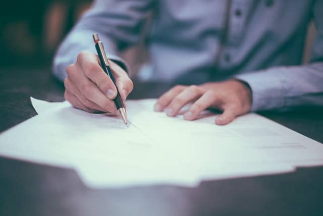 a man with a blue shirt writing a letter